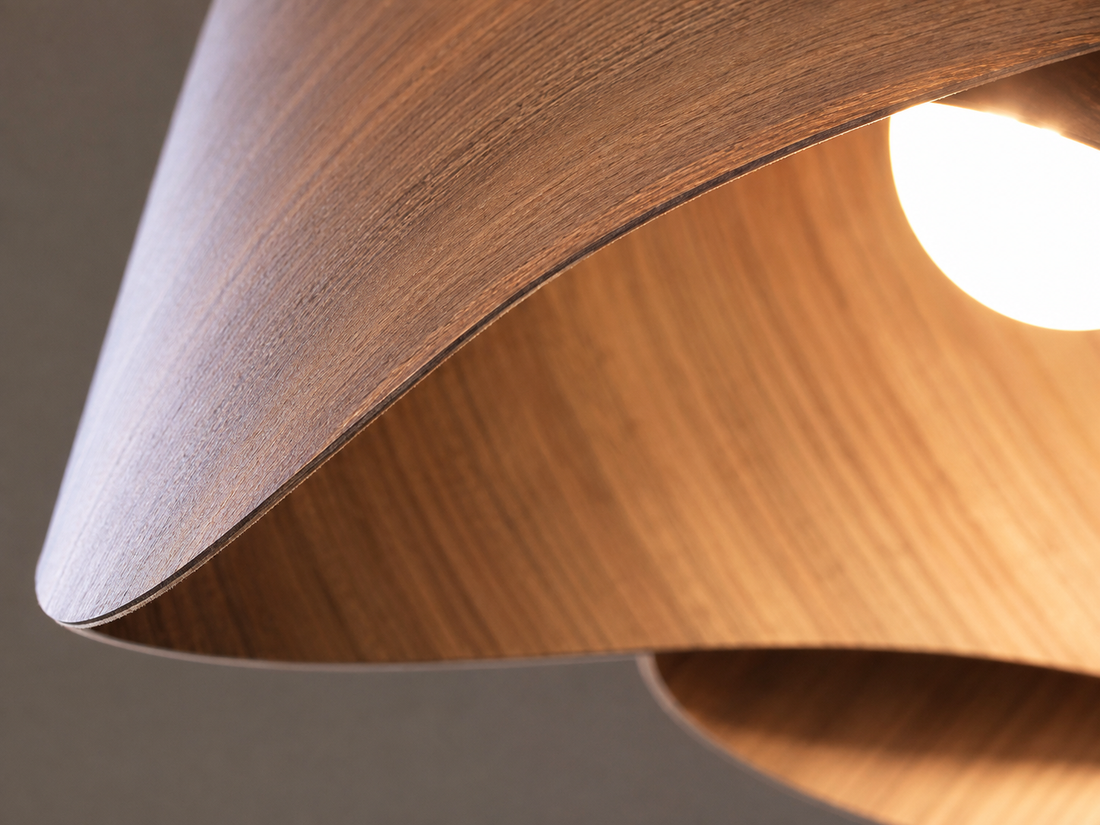 Three wood veneer pendant lights over a kitchen island with warm oak cabinetry