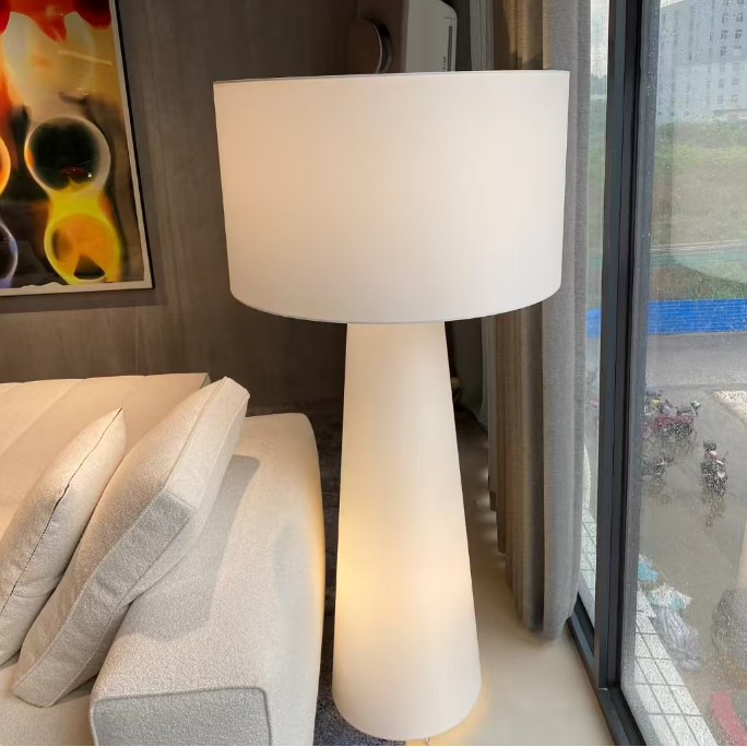 White fabric floor lamp with drum shade on long tapered pedestal