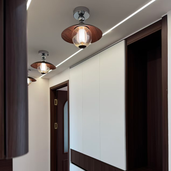 Modern hallway interior featuring white and dark wood cabinetry, recessed LED strip lighting on the ceiling, and three matching pendant lights with wood-look shades and clear glass shades.