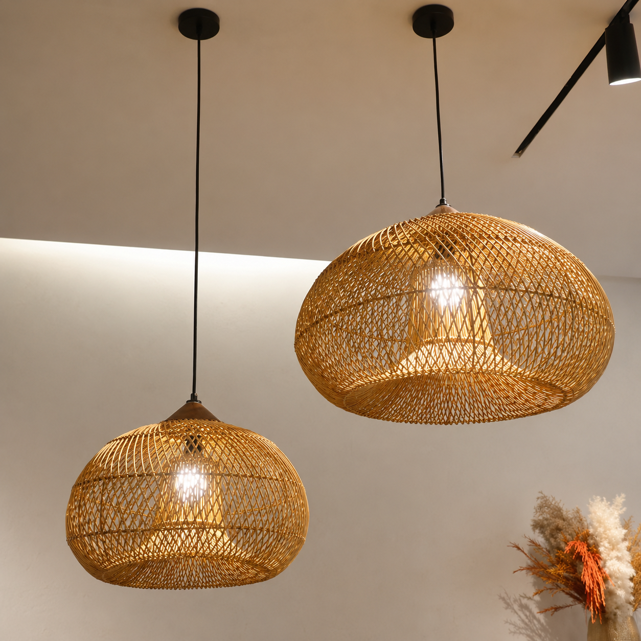 Pair of tan rattan pendant lights with woven dome shades and glowing bulbs.