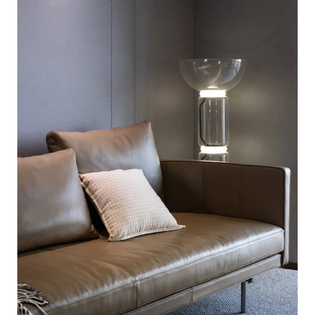 Tall glass floor lamp with clear cylindrical body and black base.