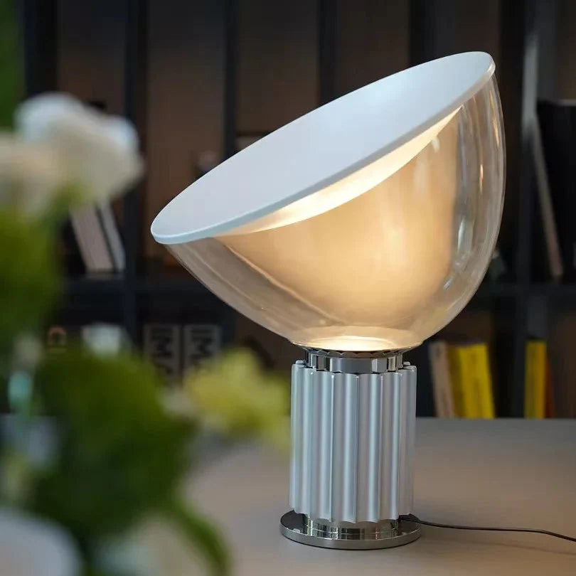 Clear dome saucer table lamp with silver ribbed base and warm lit glow