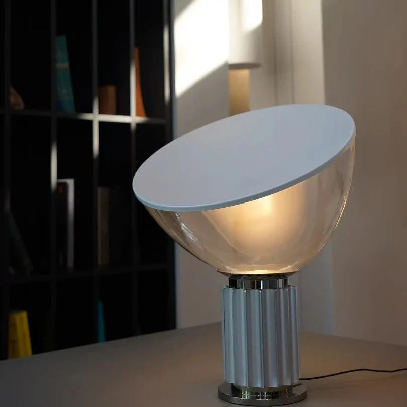 Clear dome saucer table lamp with silver ribbed base and warm lit glass shade