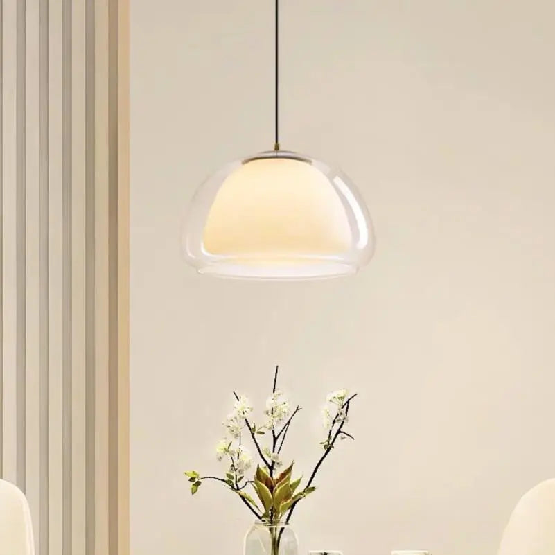 Curved glass pendant light with clear dome shade hanging from a cord.