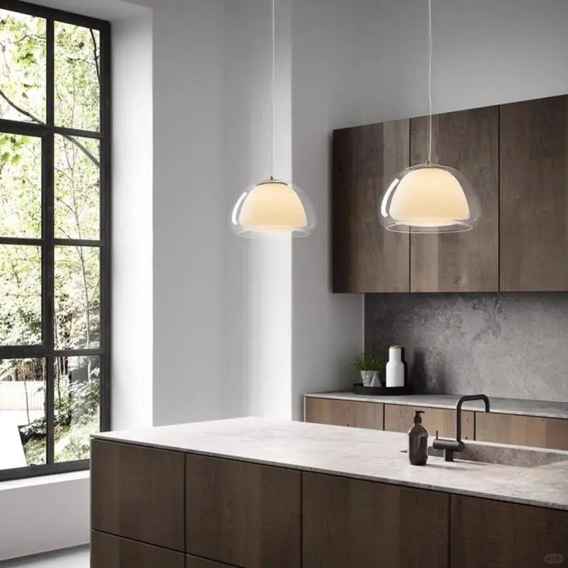Curved glass pendant light pair with rounded dome shades and gold caps