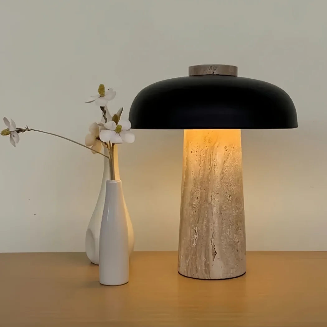 Mushroom table lamp with black dome shade and textured beige travertine base, lit from inside