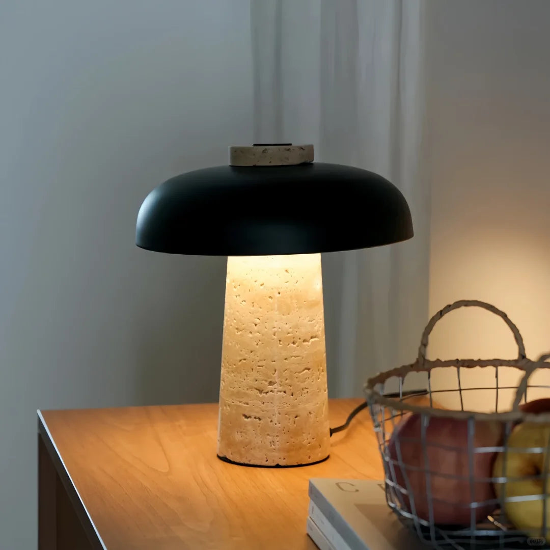 Black mushroom table lamp with beige travertine pedestal base and warm lit interior
