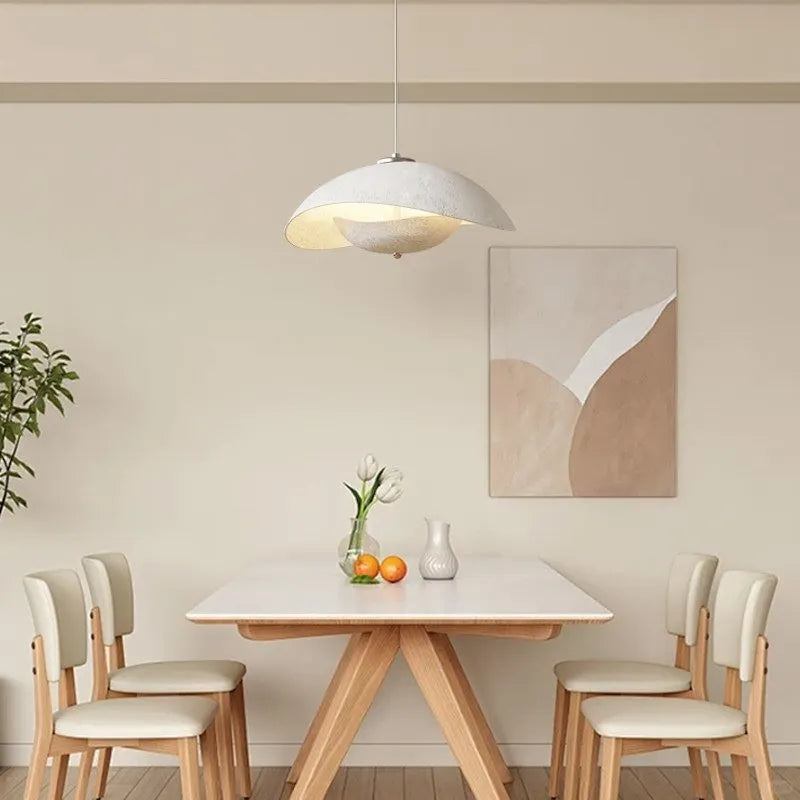 Aluminum wave pendant light with textured outer shade and warm inner illumination