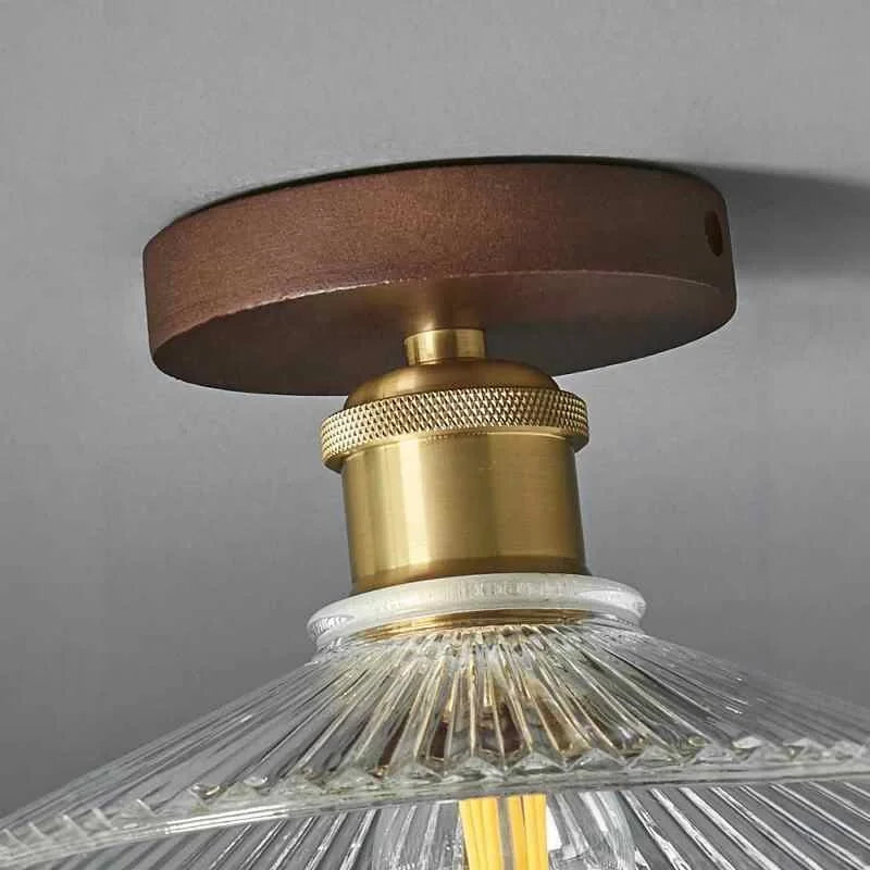 Close-up of semi-flush ceiling light with clear petal glass shade and brass fittings