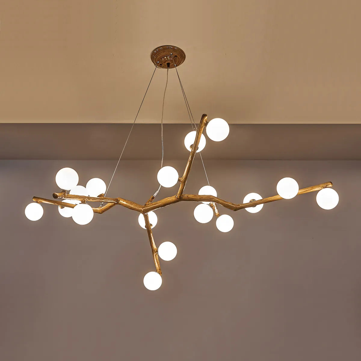 Close-up branch chandelier with dark arms, brass joints, and white globe bulbs
