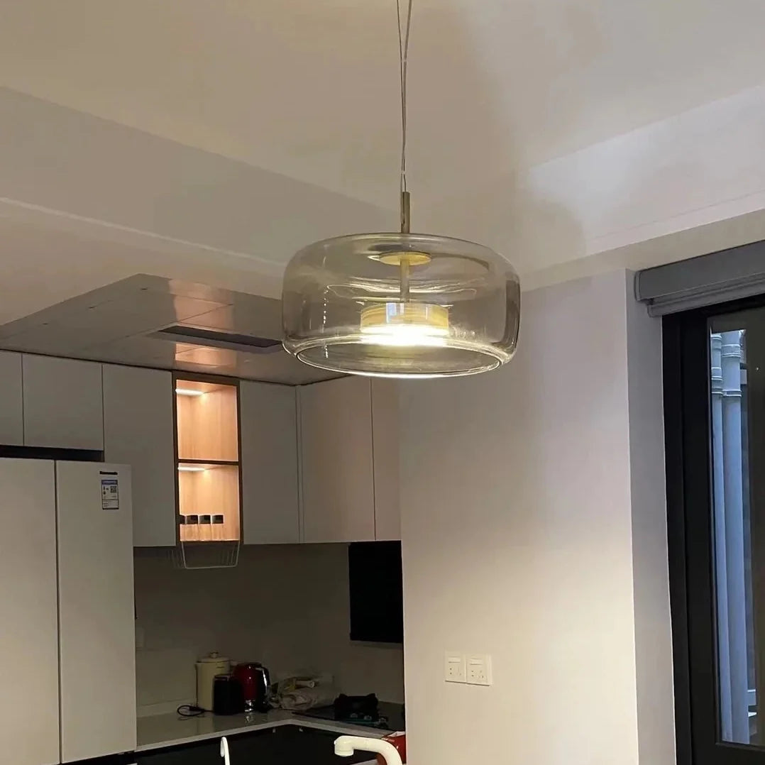 Glass dome pendant light with brass canopy and warm glowing bulb