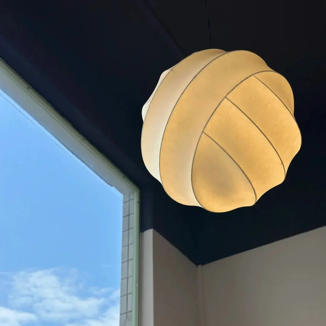 Luma silk pendant light with golden-beige pleated shade, emitting soft glow