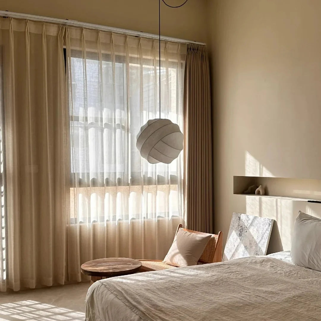 Luma silk pendant light with light beige pleated shade above a bed area
