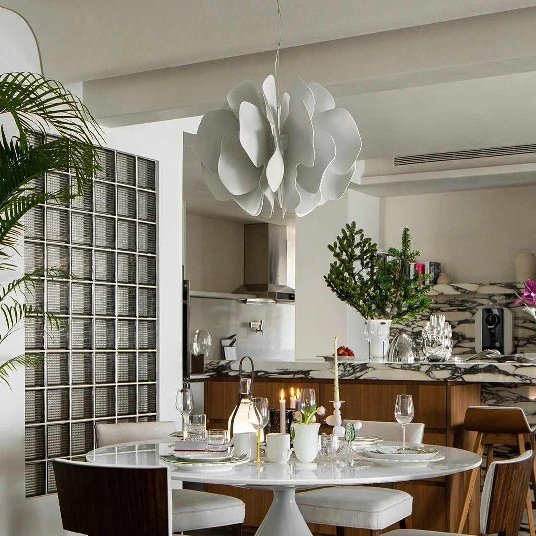 White ceramic petal chandelier with curved petal shades hanging over dining setup