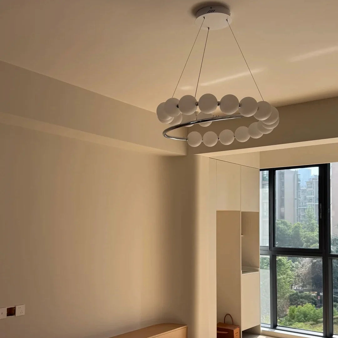 Pearl spiral chandelier with white globe shades and a chrome ring border in ceiling view