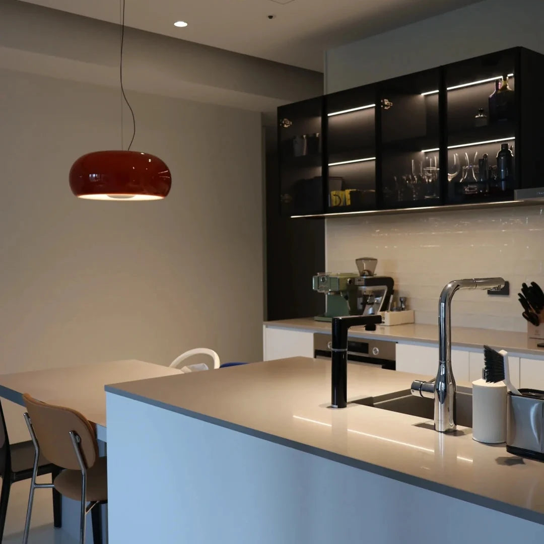 Amber blown glass pendant light with oval dome glass shade and black hanging cord.