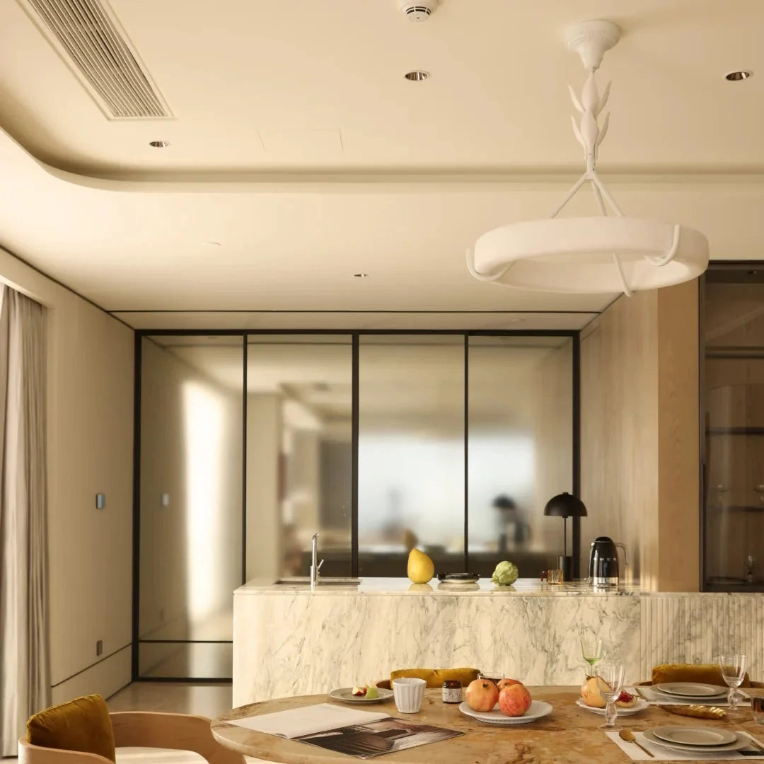 White circular chandelier with leaf-like central stem hanging above a kitchen island