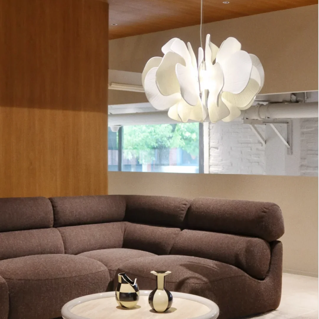 Ceramic petal chandelier with white layered petals and glowing bulb on a cord
