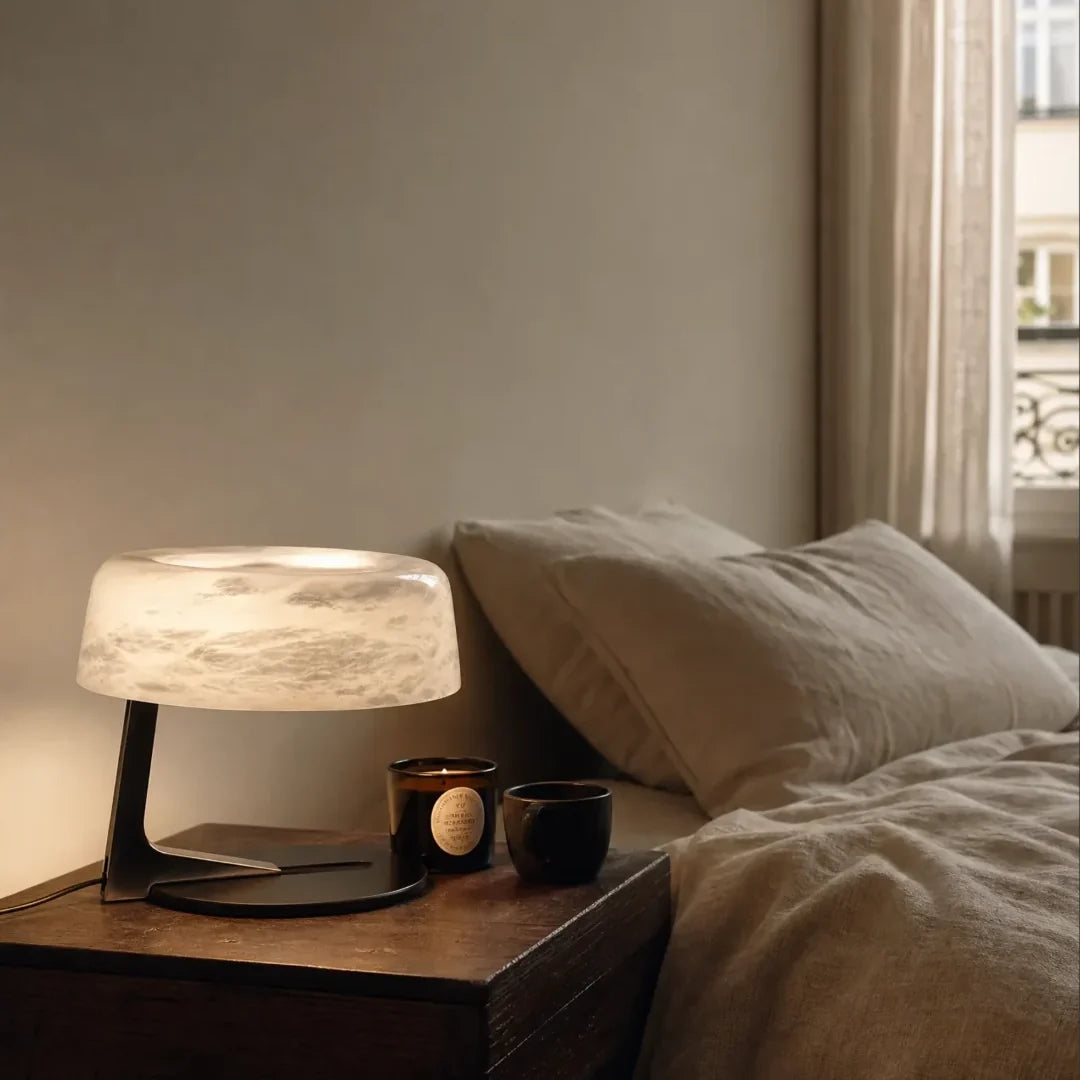 Alabaster table lamp with frosted round shade on metal base beside bedside decor