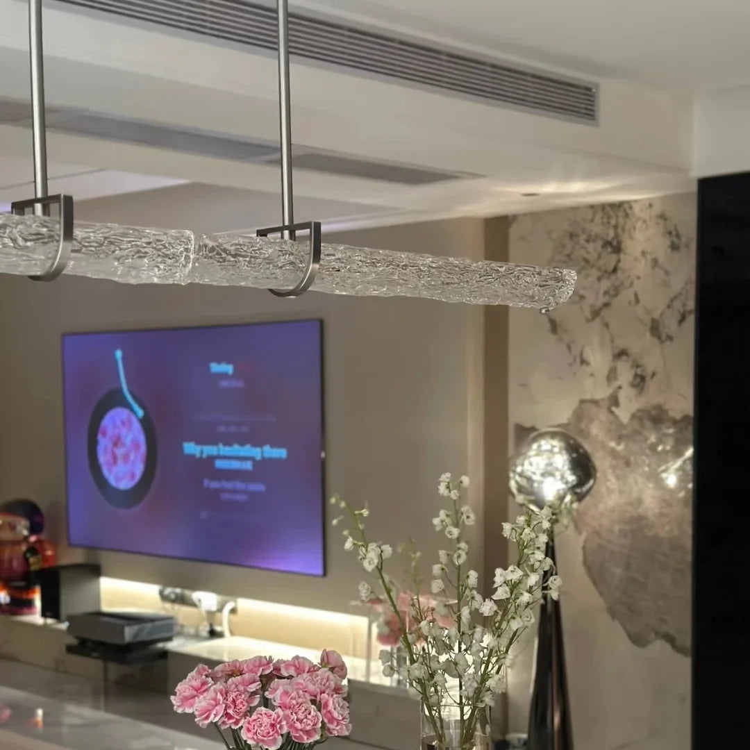 Linear pendant light detail with textured glass tube suspended from chrome frame