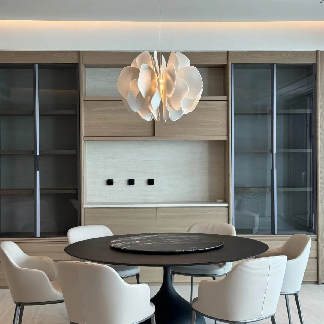 Ceramic petal chandelier centered over a dining table with layered white petal shades