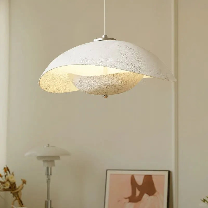 Textured gray aluminum pendant light with curved wave shade and warm light