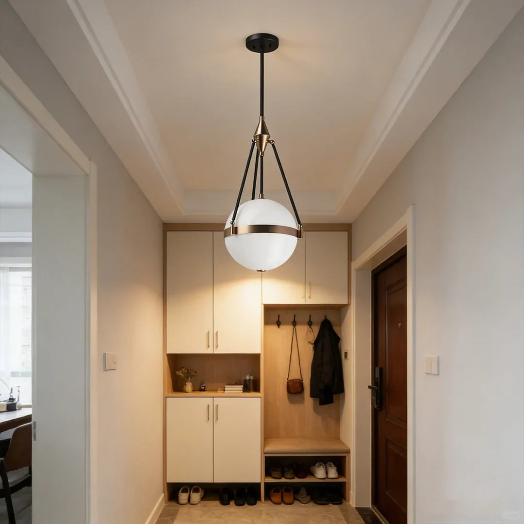 Single globe pendant light with white glass sphere, black cord, and gold metal frame