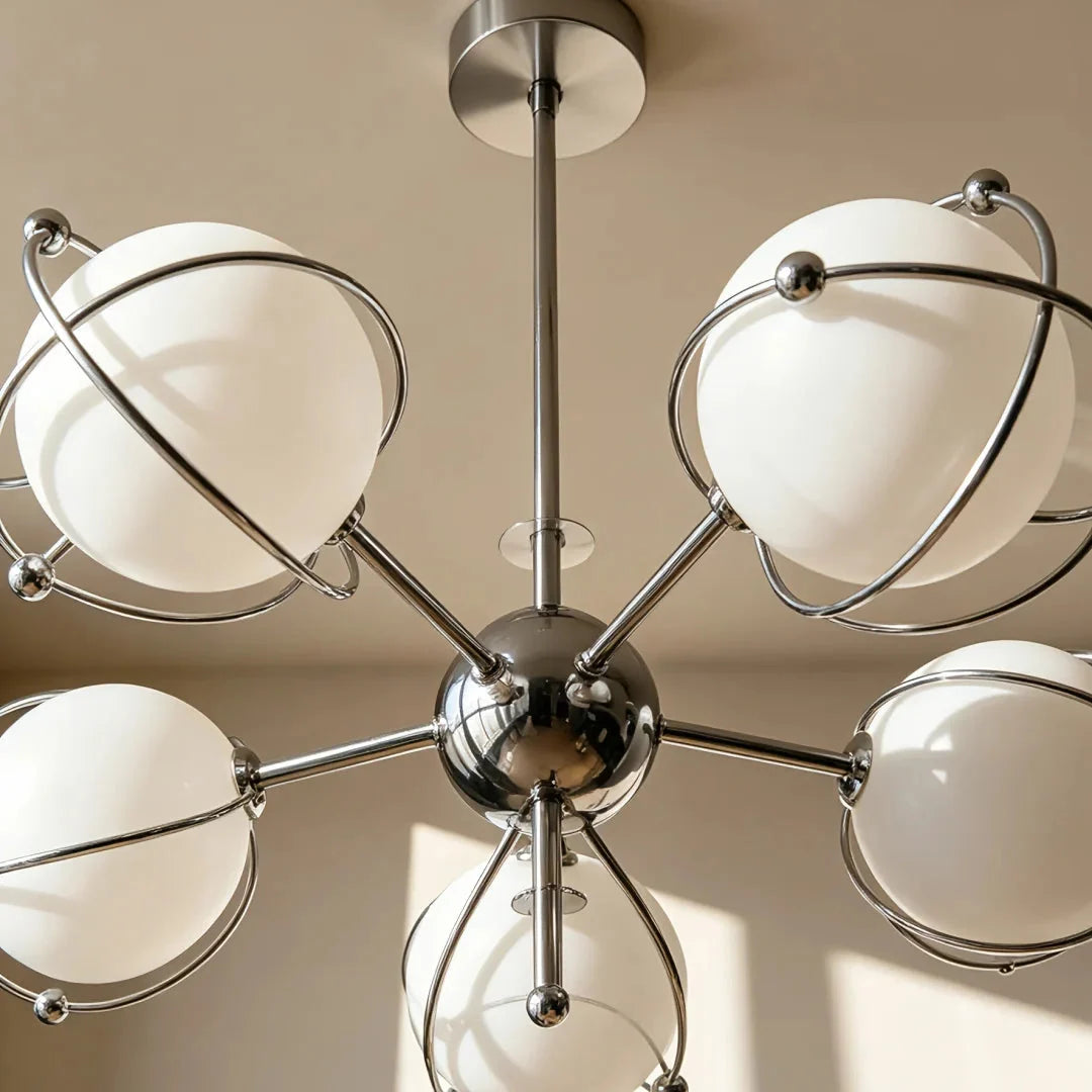 Close view of orbit-style chandelier: chrome hub with curved arms and round opal shades