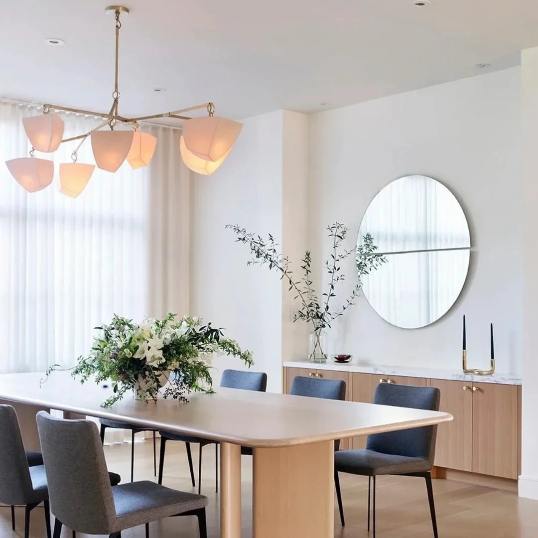 Brass branching chandelier with frosted white shades over dining area near window