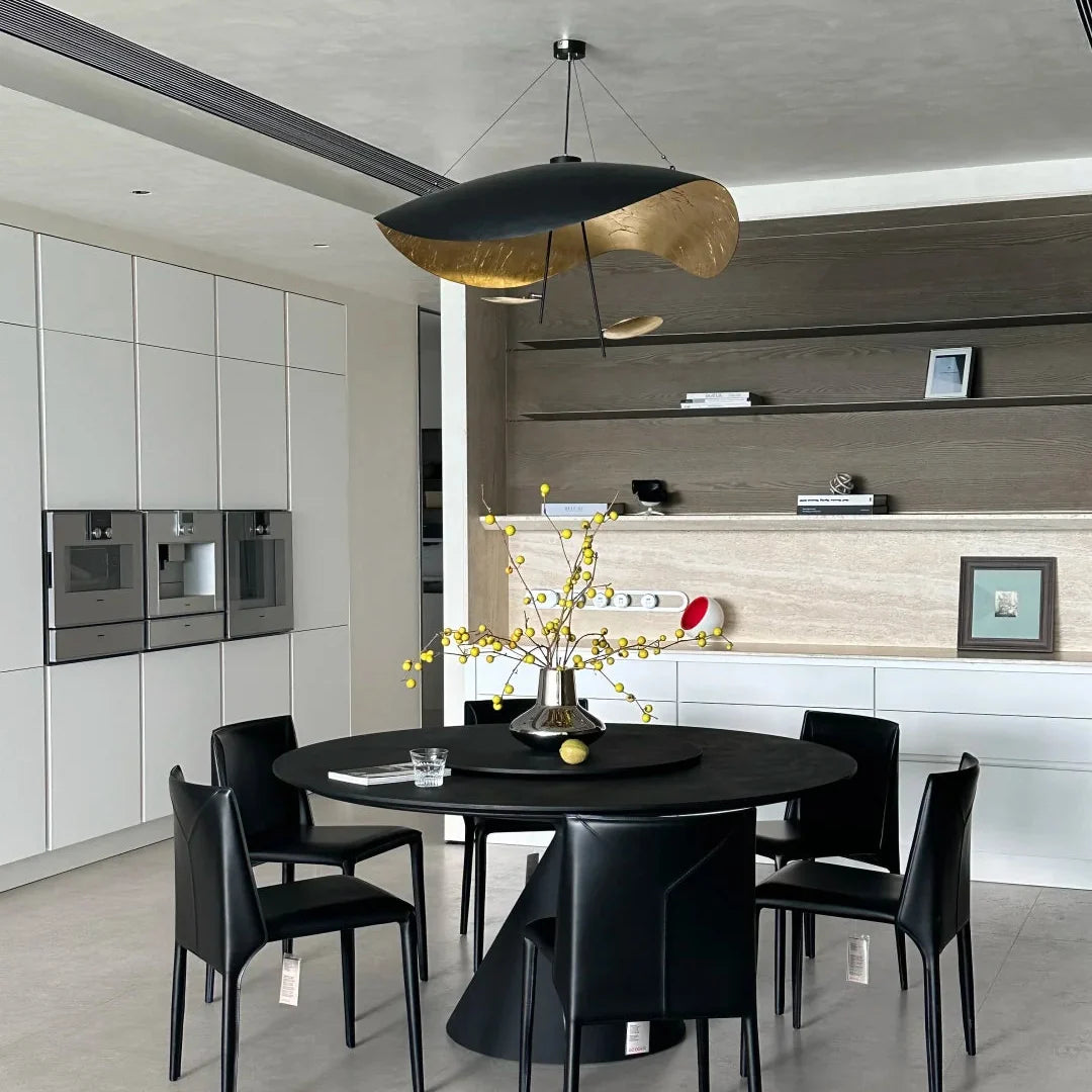 Black and gold foil disc pendant light hanging above a dining area