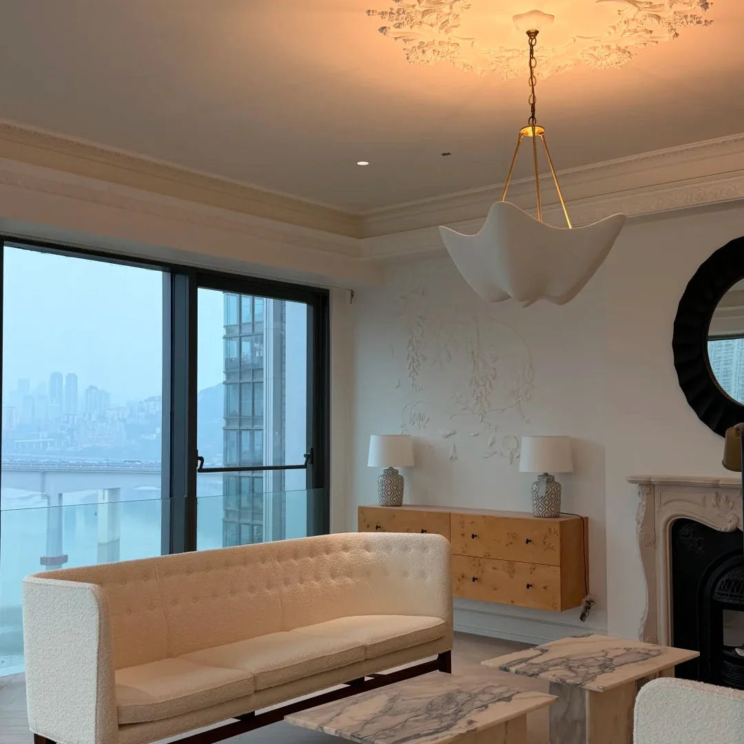Chalk white plaster chandelier with wide petal shade hanging from a ceiling frame