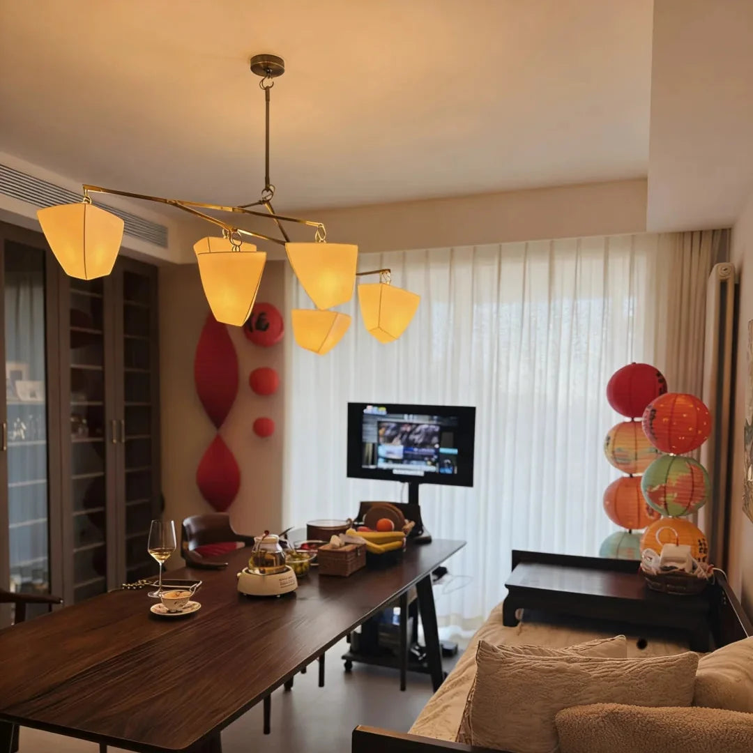 Brass branching chandelier with warm yellow frosted shades in living room dining space
