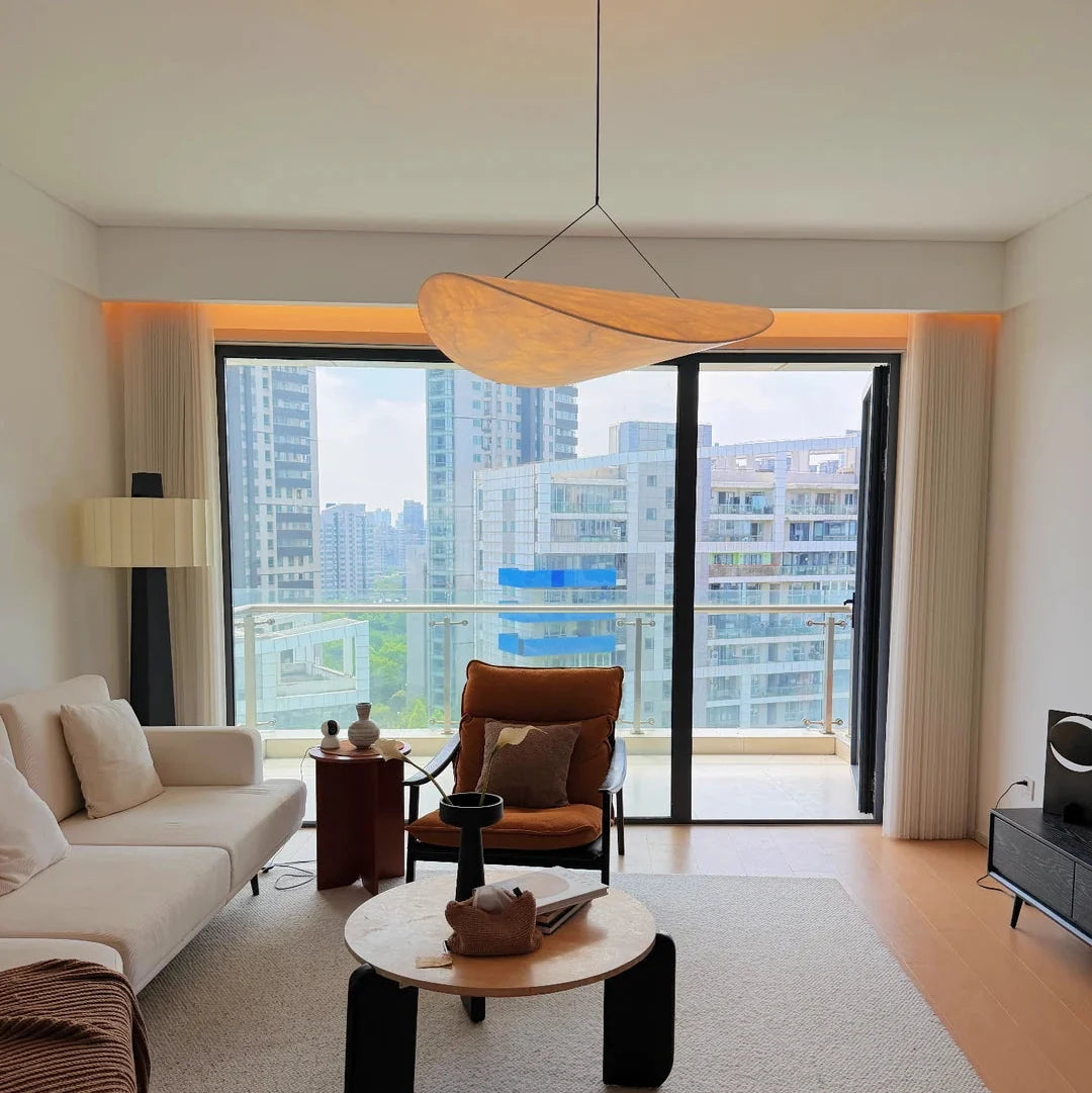 Paper pendant light with light wood oval shade hanging from ceiling.