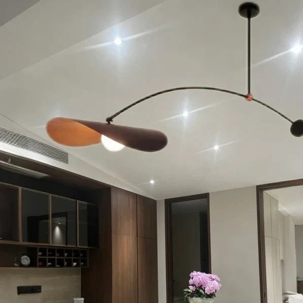 Single-arm pendant light with black curved arm and gold inner shade, ceiling-mounted