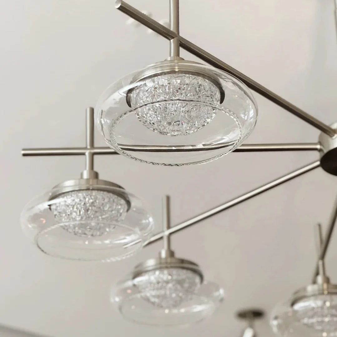 Close-up of spider chandelier clear glass shades on brushed metal arms.