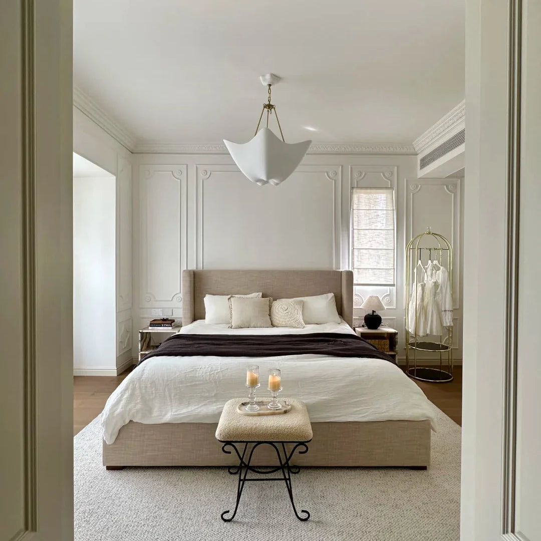 Chalk white plaster chandelier with two-tiered petal shade over a bed