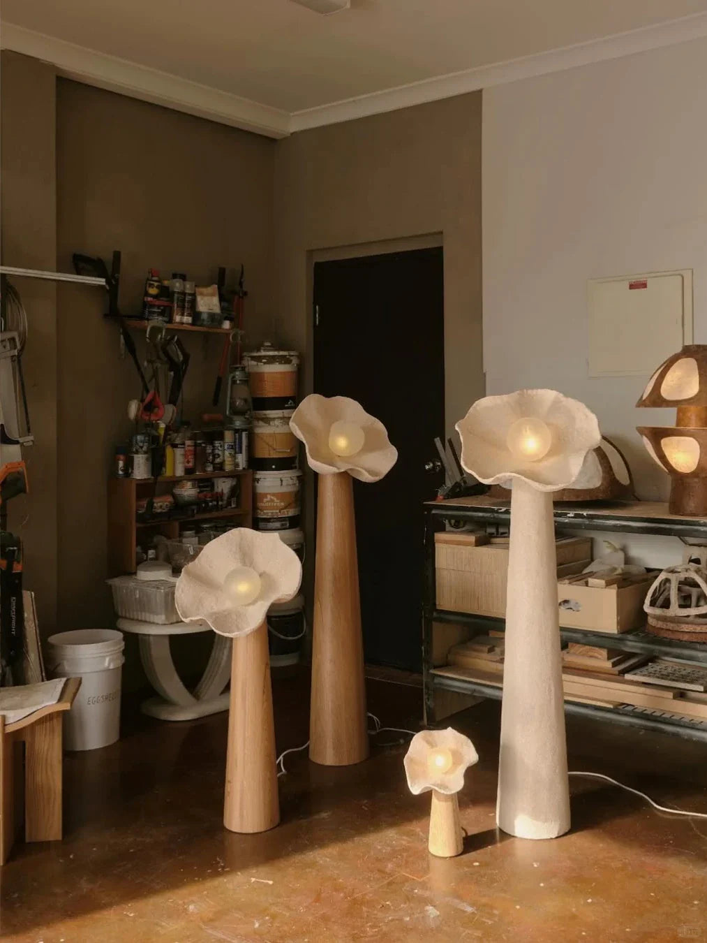 Several mushroom floor lamps in warm room lighting, wood bases with lit textured shades