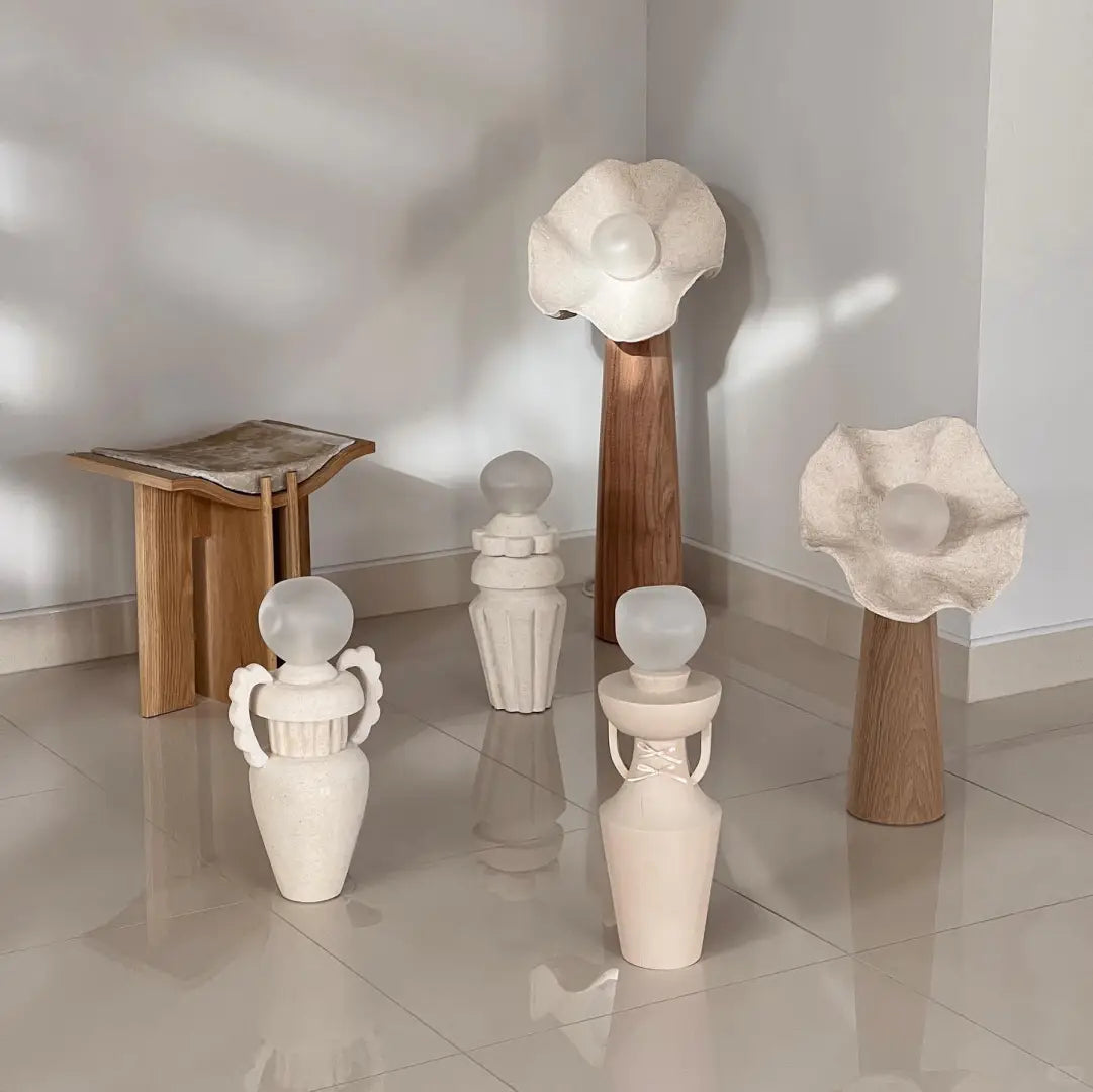 Several mushroom floor lamps with wood stems and lit textured shades in bright room