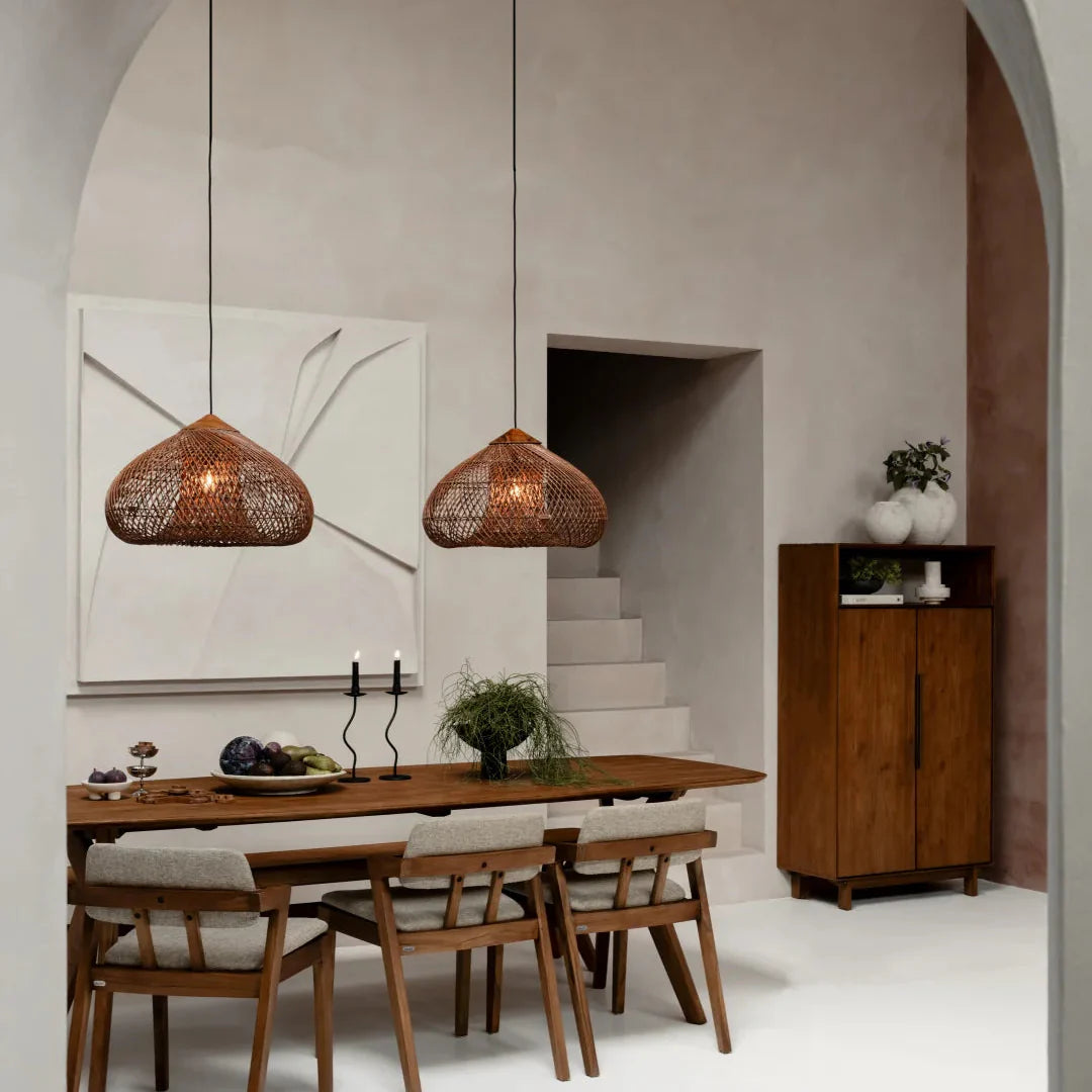 Three rattan pendant lights with woven dome shades over a long dining table.