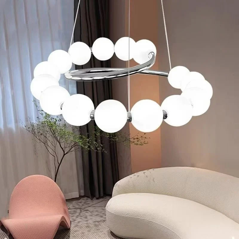 Close-up of pearl spiral chandelier: white globe shades around a chrome ring bar