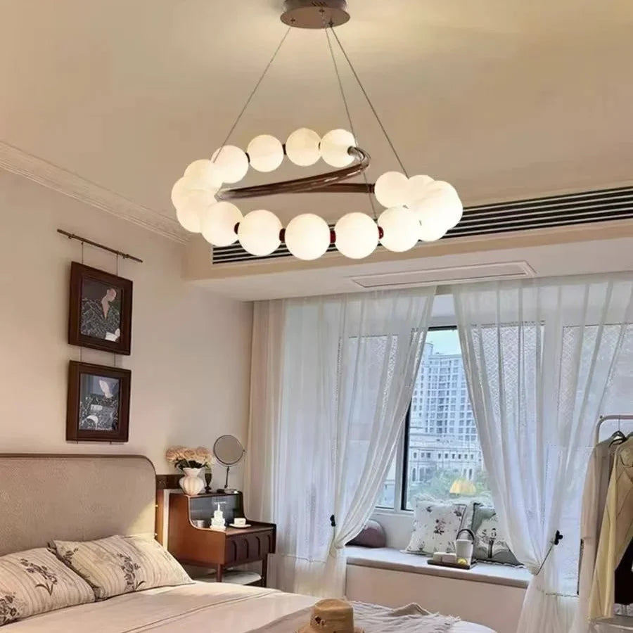 Pearl spiral chandelier with white globe shades hanging from a dark ring frame