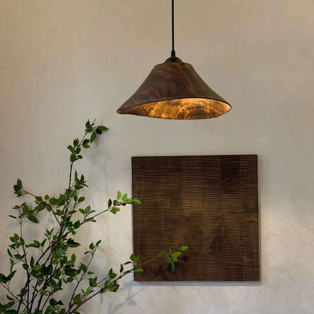 Cone wood pendant light with dark amber wood shade and warm bulb, hanging from cord