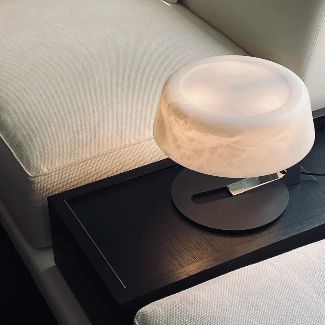 Alabaster table lamp with round frosted shade and black base on a sofa table