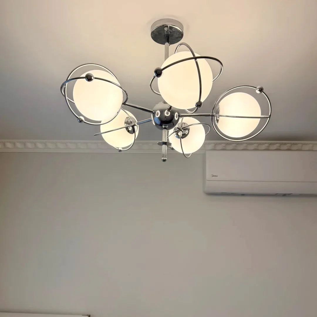 Orbit chandelier with central chrome hub, circular metal rings, and frosted shades
