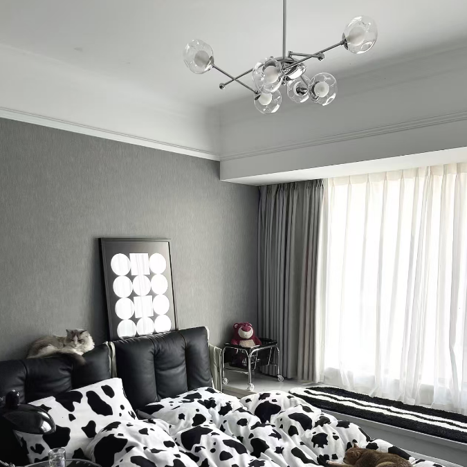 Modern globe chandelier with clear glass shades and chrome arms over seating area