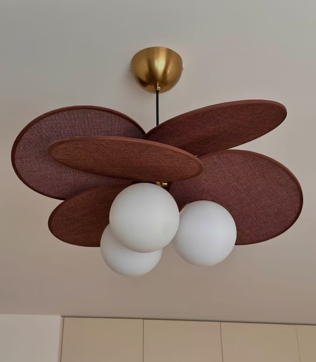 Walnut fabric petal pendant light with brass canopy, five dark petals, three white globe shades