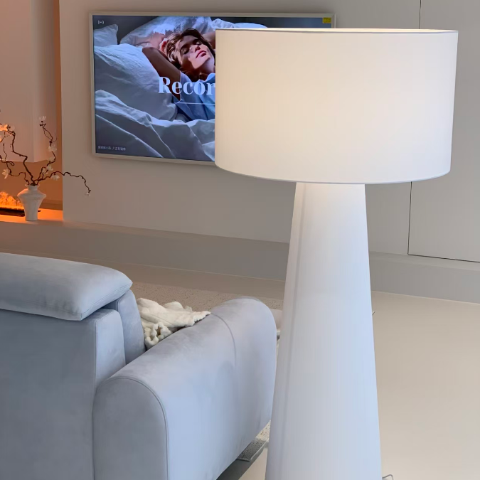 White fabric floor lamp with wide drum shade on tall cylindrical stem