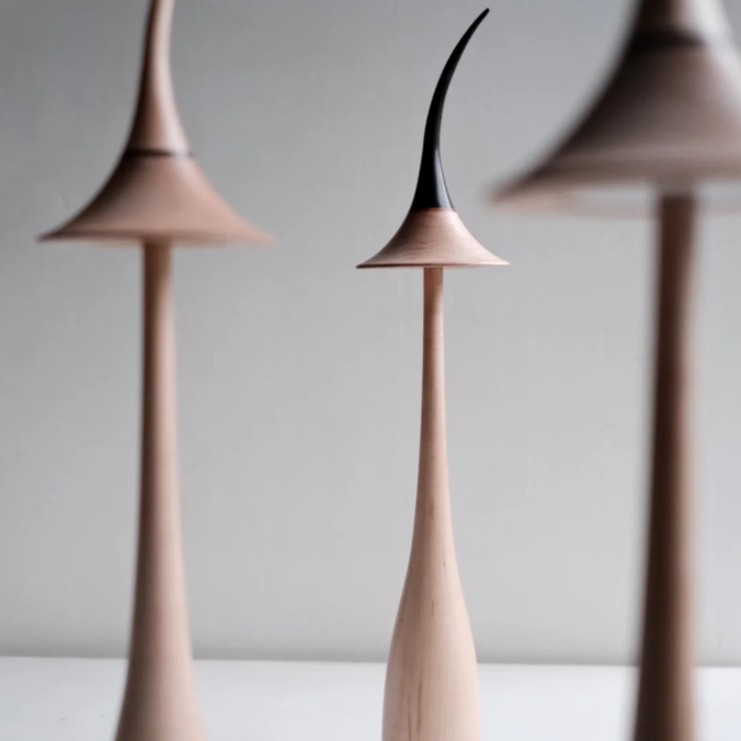 Pair of maple wood cordless table lamps with curved shades in light and black.