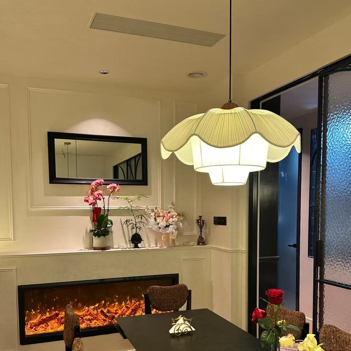 French linen pendant light with scalloped petal shade, glowing over fireplace seating area.