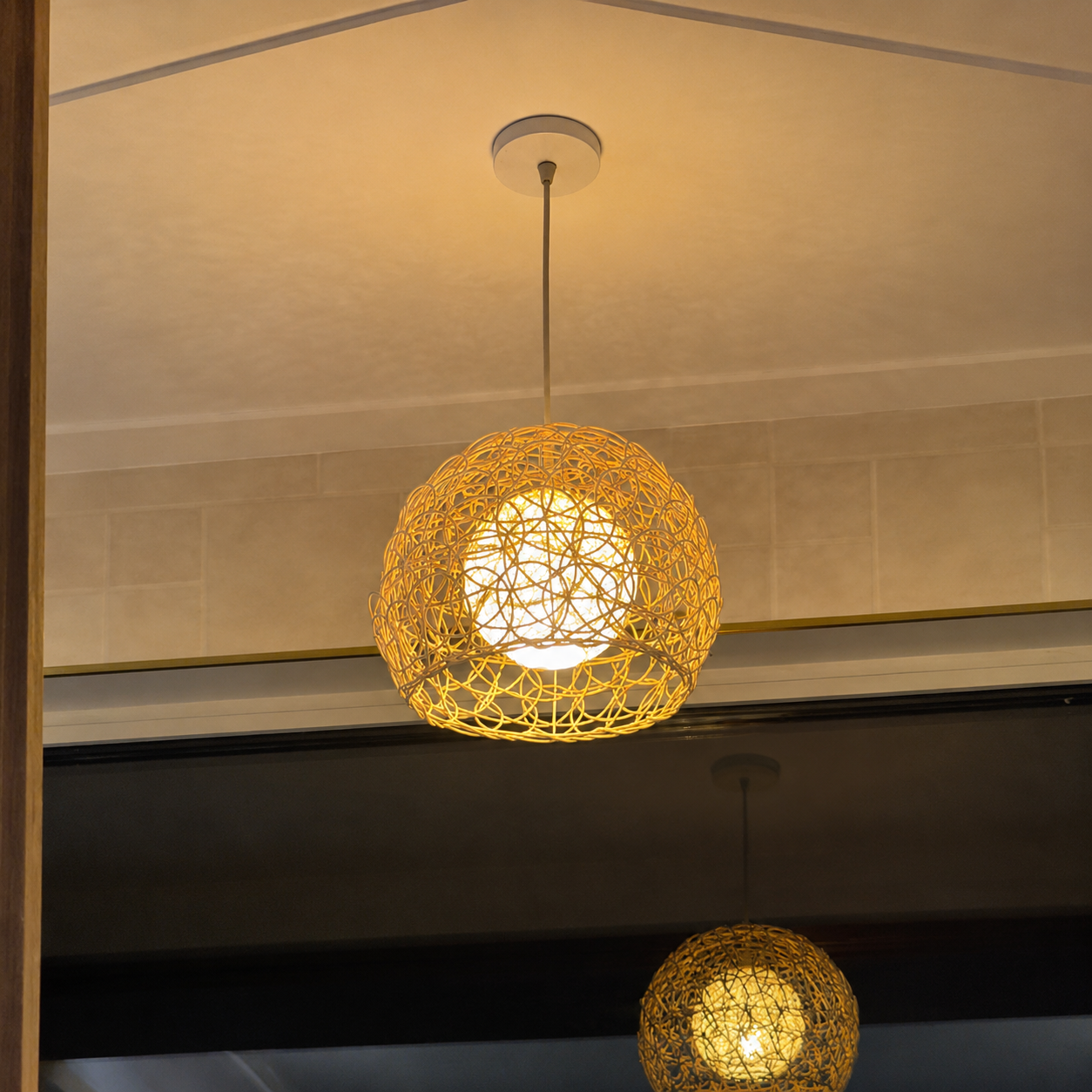 Rattan orb pendant light with woven lattice shade hanging from ceiling, warm glow